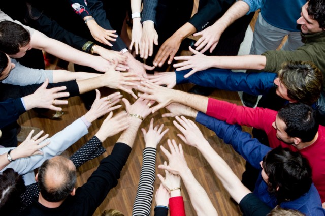 Hands reaching into a circle in a community cheer